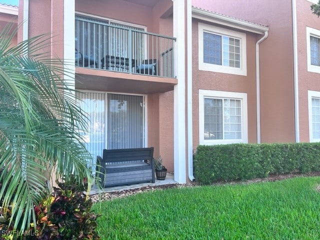 doorway to property featuring a balcony and a lawn