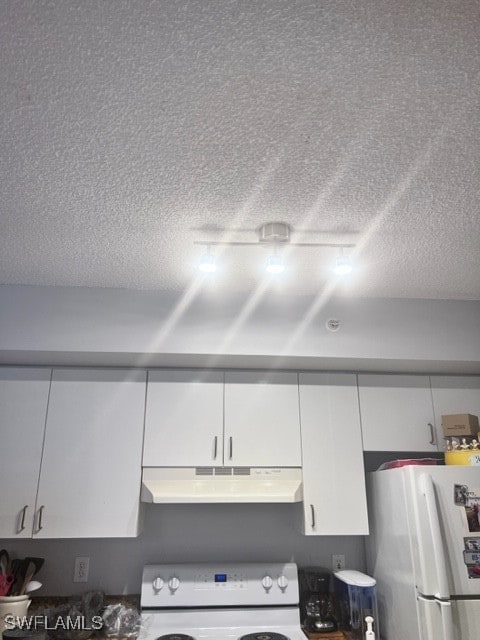 interior details with a textured ceiling, range, white refrigerator, and white cabinets