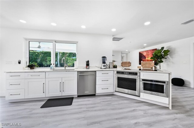 kitchen featuring appliances with stainless steel finishes, sink, white cabinets, and kitchen peninsula