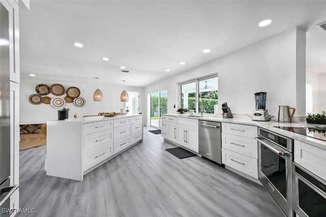 kitchen featuring sink, decorative light fixtures, light hardwood / wood-style flooring, stainless steel appliances, and white cabinets