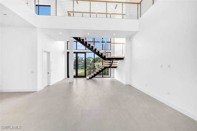 interior space featuring a towering ceiling, stairs, baseboards, and recessed lighting