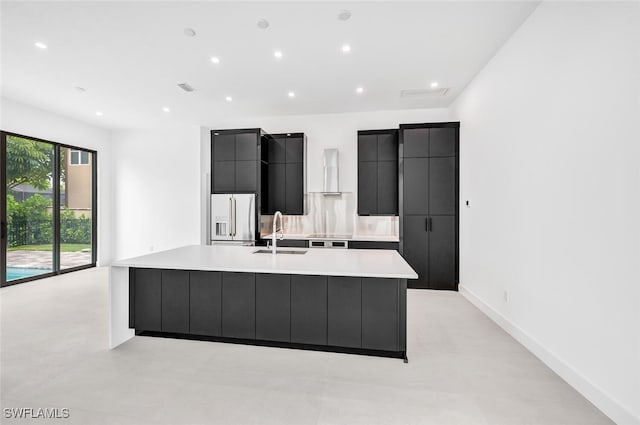 kitchen with a large island, high quality fridge, dark cabinets, light countertops, and a sink