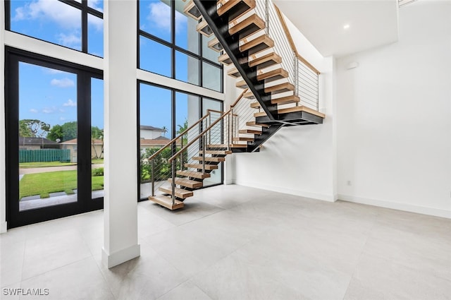 interior space featuring a towering ceiling, stairs, and baseboards