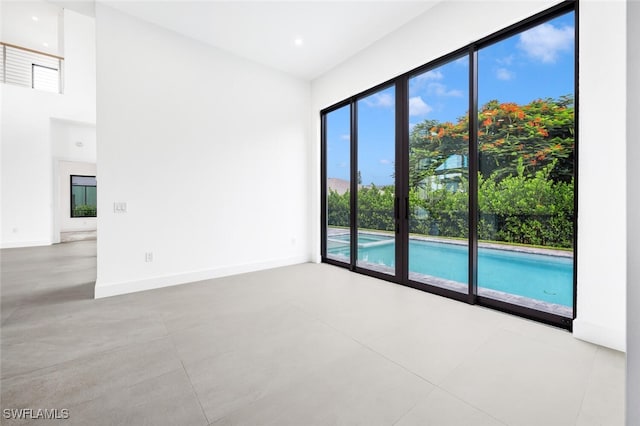 spare room with recessed lighting, a towering ceiling, and baseboards