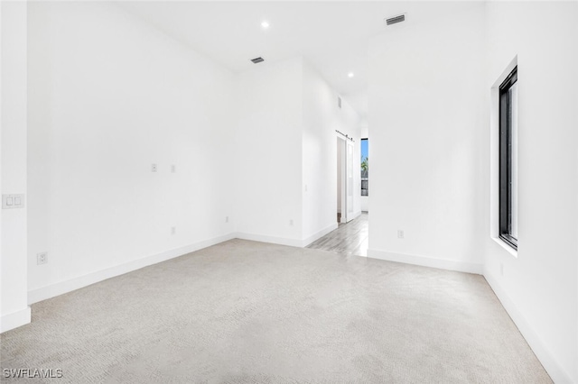 empty room featuring light carpet, baseboards, and recessed lighting