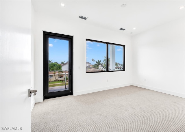 spare room with light colored carpet, visible vents, and baseboards