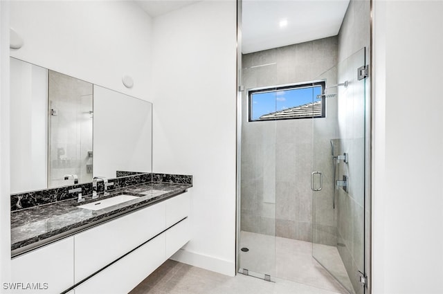 full bath featuring a stall shower, tile patterned flooring, vanity, and baseboards