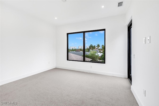 empty room featuring baseboards, visible vents, and light colored carpet