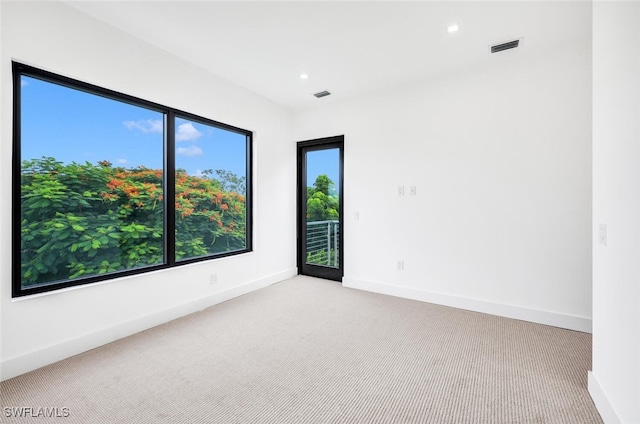 empty room featuring recessed lighting, light colored carpet, visible vents, baseboards, and a healthy amount of sunlight