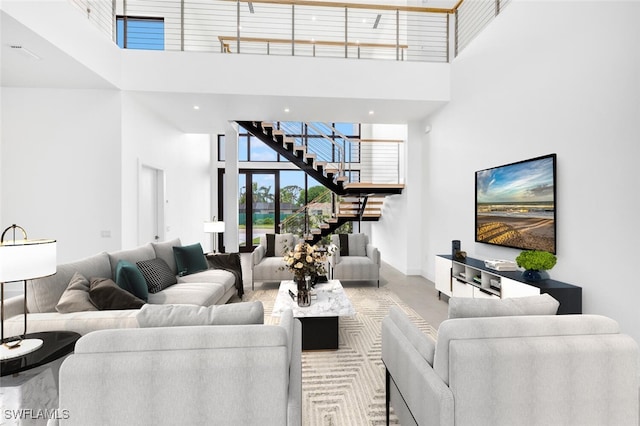 living area featuring a towering ceiling, baseboards, and stairs