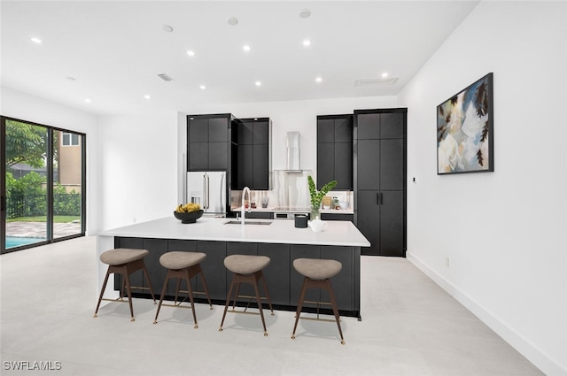 kitchen with a large island, high quality fridge, a sink, dark cabinets, and a kitchen bar