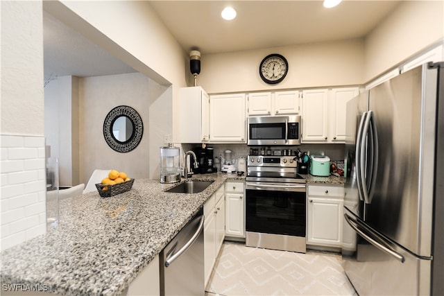 kitchen with light tile patterned floors, appliances with stainless steel finishes, sink, backsplash, and light stone counters