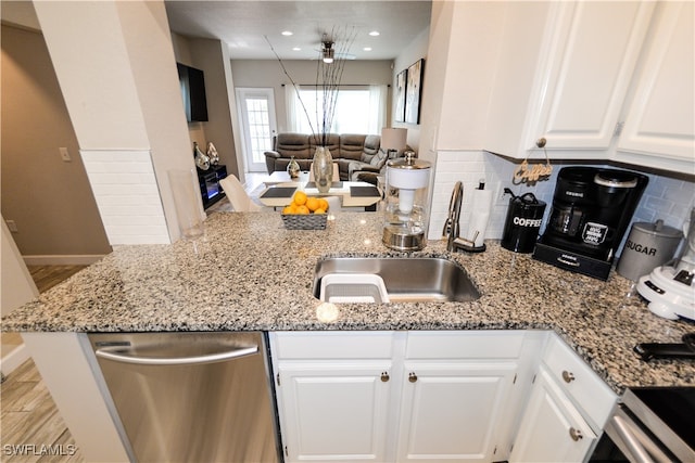 kitchen with backsplash, light stone counters, white cabinetry, and stainless steel dishwasher