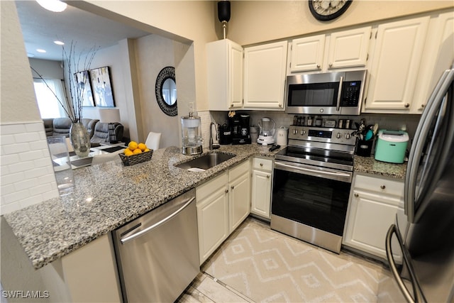 kitchen featuring tasteful backsplash, stainless steel appliances, white cabinetry, and light stone countertops