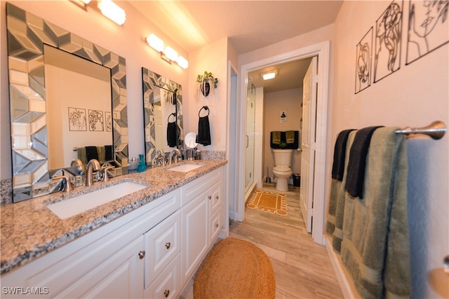 bathroom with dual vanity, toilet, and hardwood / wood-style floors