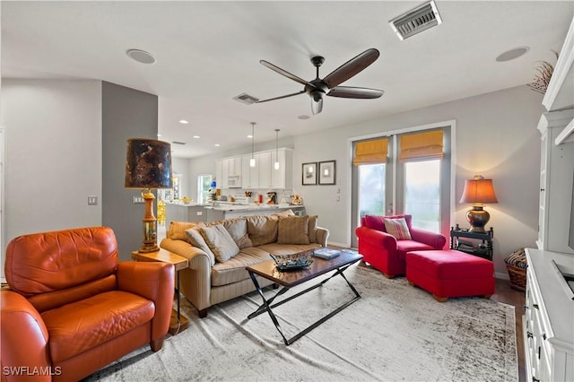 living room with a ceiling fan, a wealth of natural light, and visible vents