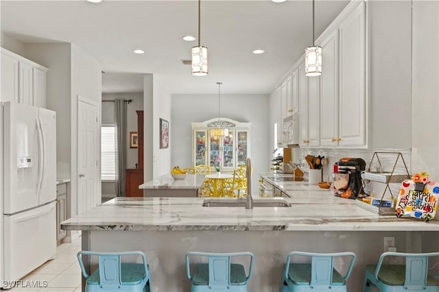 kitchen with white appliances, decorative light fixtures, a sink, and a peninsula