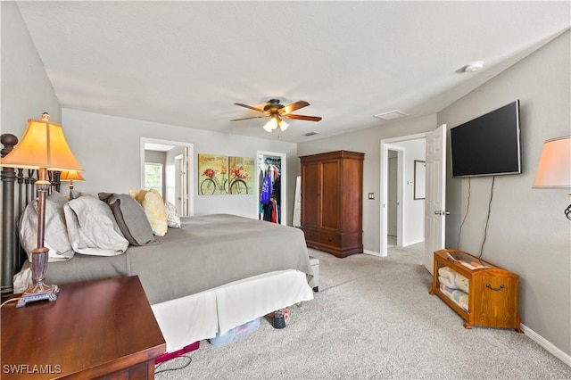 bedroom with light colored carpet, a ceiling fan, baseboards, a spacious closet, and a closet