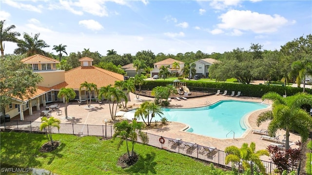 community pool featuring a residential view, fence, and a patio