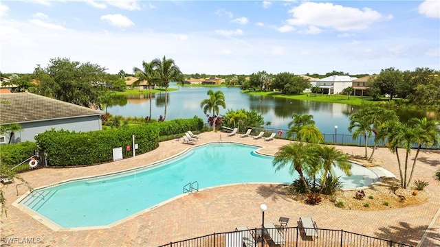 pool featuring a patio area, a water view, and fence