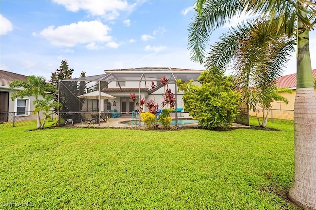 rear view of house with an outdoor pool, glass enclosure, a lawn, and fence