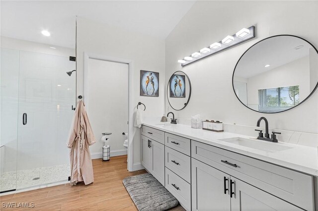 bathroom featuring an enclosed shower, lofted ceiling, dual bowl vanity, wood-type flooring, and toilet