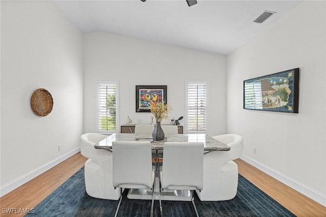 dining space with lofted ceiling, visible vents, baseboards, and wood finished floors