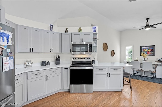 kitchen featuring light wood-style flooring, stainless steel appliances, vaulted ceiling, light countertops, and open shelves