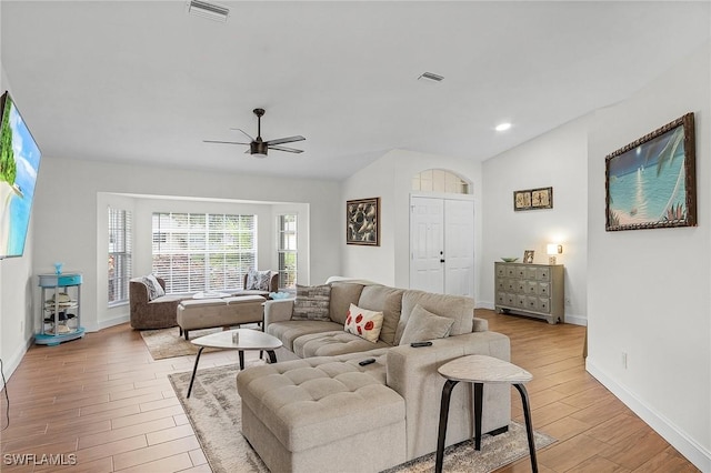 living room featuring baseboards, visible vents, a ceiling fan, vaulted ceiling, and light wood-type flooring