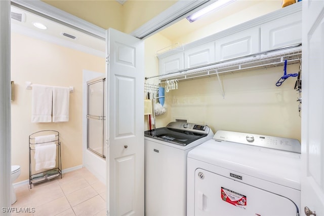 clothes washing area with washing machine and dryer, light tile patterned flooring, and crown molding