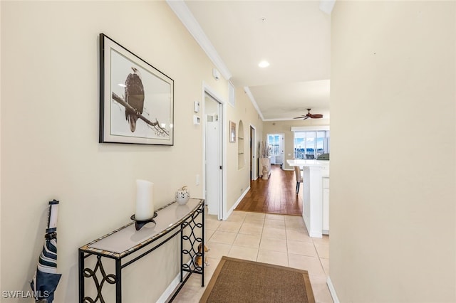 corridor with light hardwood / wood-style flooring and ornamental molding