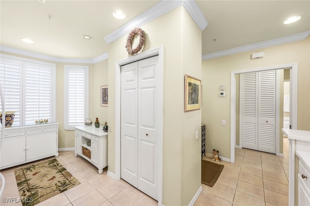 foyer with light tile patterned floors and crown molding