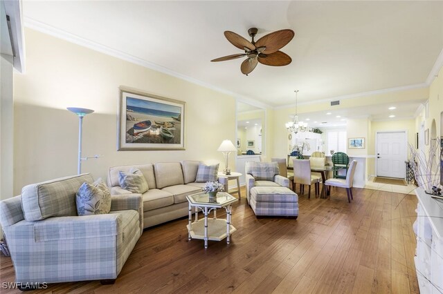 living room with hardwood / wood-style floors, ornamental molding, and ceiling fan with notable chandelier