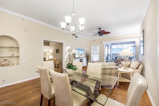 dining room with built in shelves, hardwood / wood-style flooring, ceiling fan with notable chandelier, and ornamental molding