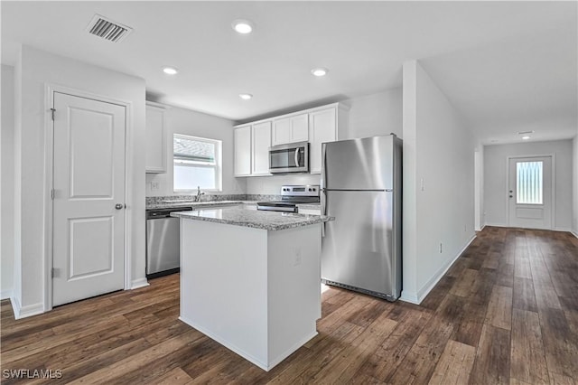 kitchen with stainless steel appliances, dark wood-type flooring, white cabinetry, visible vents, and a center island