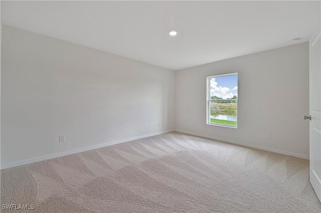 spare room featuring light carpet and baseboards