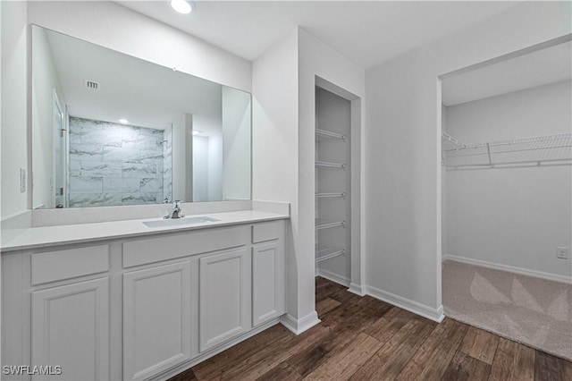 full bath with a marble finish shower, visible vents, baseboards, wood finished floors, and vanity