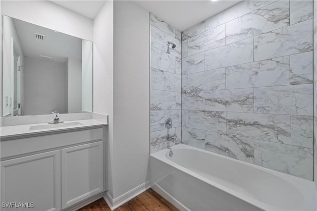 full bathroom with shower / bath combination, baseboards, visible vents, wood finished floors, and vanity