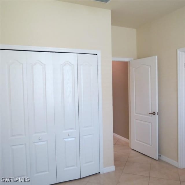 unfurnished bedroom with light tile patterned flooring and a closet