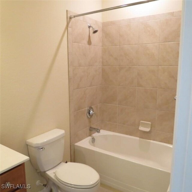 full bathroom featuring tiled shower / bath, vanity, and toilet