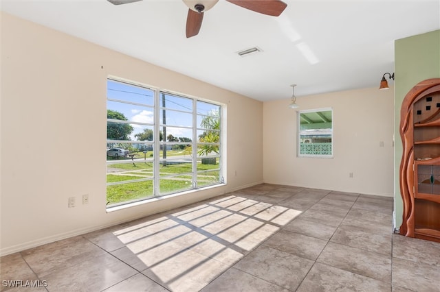 unfurnished room with ceiling fan, light tile patterned flooring, and a healthy amount of sunlight