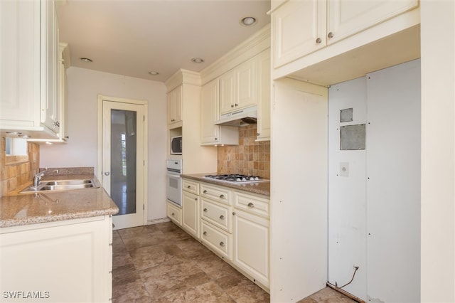 kitchen featuring tasteful backsplash, appliances with stainless steel finishes, light stone counters, light tile patterned floors, and sink