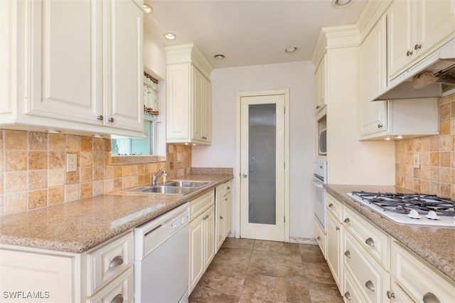 kitchen featuring white appliances, light stone countertops, light tile patterned flooring, tasteful backsplash, and sink