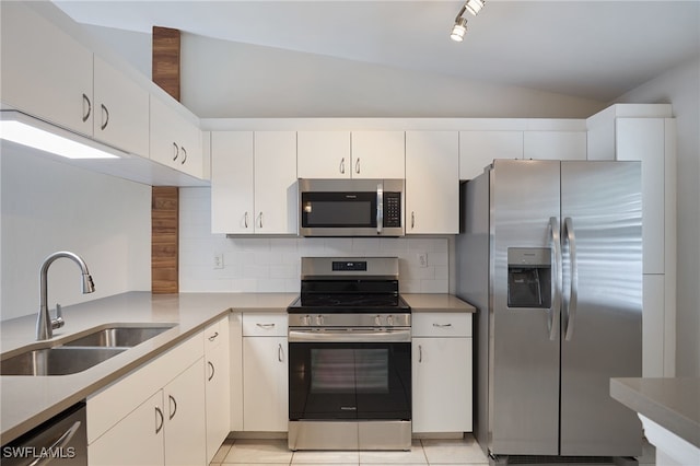 kitchen featuring lofted ceiling, stainless steel appliances, sink, light tile patterned floors, and white cabinetry