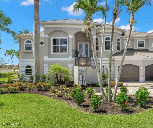 view of front of property featuring a garage, french doors, and a front lawn