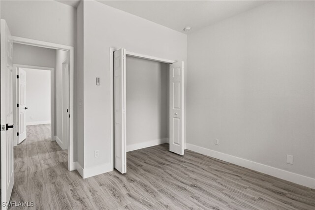 unfurnished bedroom featuring light wood-type flooring and a closet