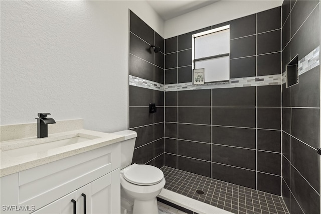 bathroom featuring vanity, toilet, and tiled shower