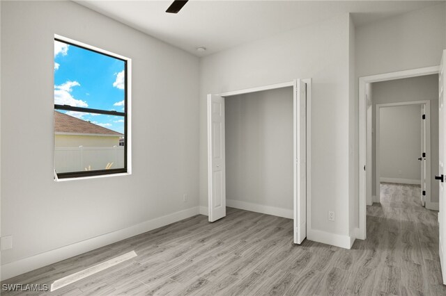 unfurnished bedroom with a closet, light hardwood / wood-style floors, and ceiling fan