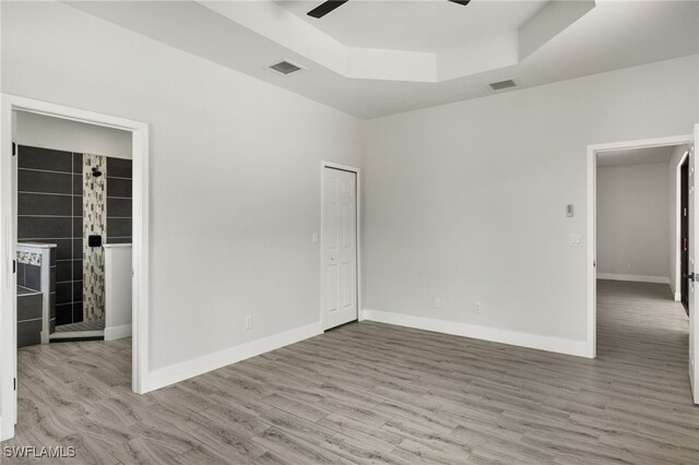 spare room featuring wood-type flooring, ceiling fan, and a raised ceiling