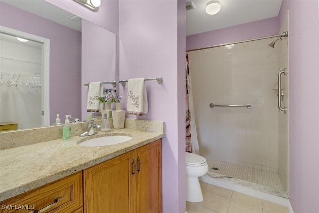 bathroom with tile patterned floors, toilet, vanity, and a tile shower